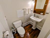 Toilet, hand sink, mirror, towel rack, wood floors