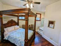 Queen size bed with four post frame, ceiling fan, wood floors