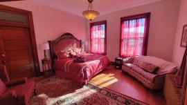 Gorgeous room decorated in rich deep reds and golds featuring a king size bed, 2 person soaking tub, and walk in shower