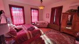 Gorgeous room decorated in rich deep reds and golds featuring a king size bed, 2 person soaking tub, and walk in shower