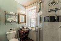 Bathroom with standing shower, antique vanity, deep window sill, and toliet.