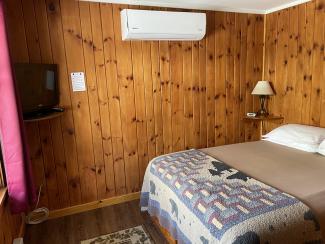 Queen bed, TV, and wall-mounted electric heater/air conditioner unit